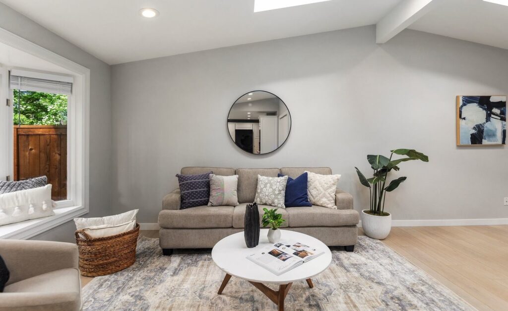 Living room with a light sofa, navy pillows and a round mirror