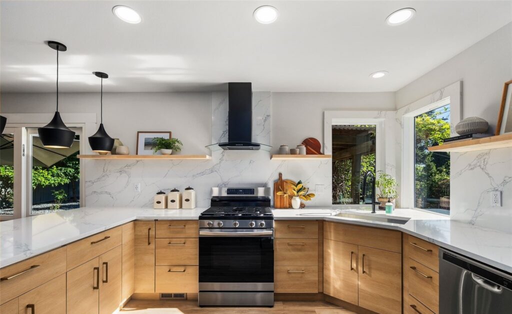 Kitchen with light wood cabinets, open shelving and black pendant lights