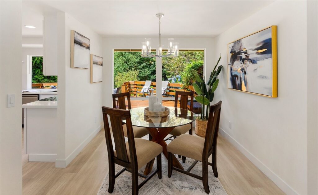 Dining table with wood chairs beside windows overlooking the trees