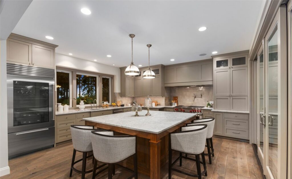 Seattle home staging in a kitchen with a large island and pendant lights, open to the living space